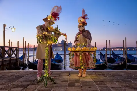 Due costumi di Carnevale sulla riva al tramonto